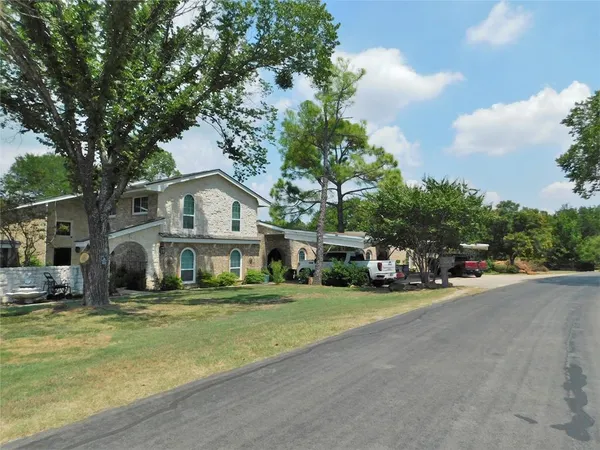 a front view of a house with a garden and trees
