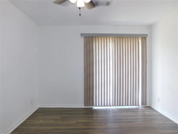 an empty room with wooden floor chandelier fan and windows
