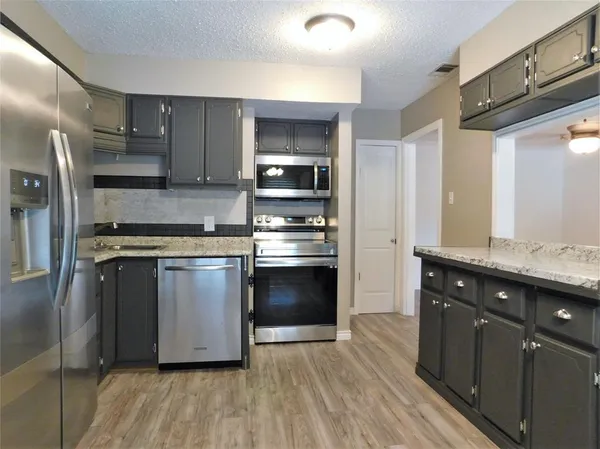 a kitchen with stainless steel appliances kitchen island granite countertop a stove and a refrigerator
