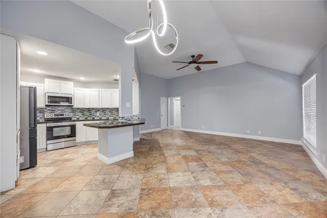 a view of kitchen with stainless steel appliances granite countertop a stove a sink dishwasher and a refrigerator with white cabinets