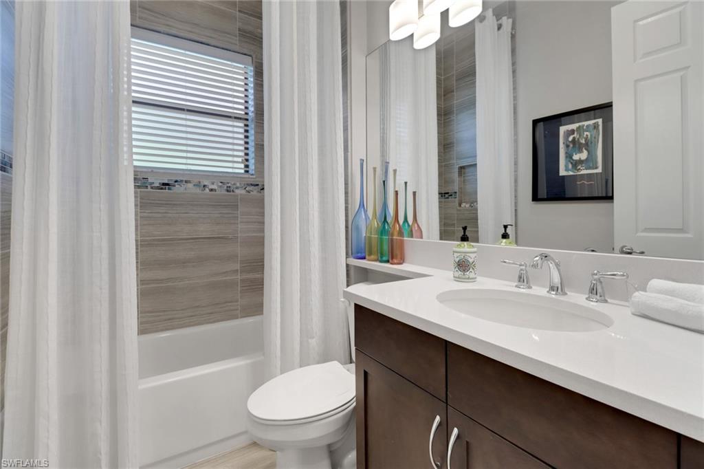 13836 Luna Drive Naples, FL 34109 - Photo 18 of 36 a bathroom with a granite countertop sink toilet a mirror and shower
