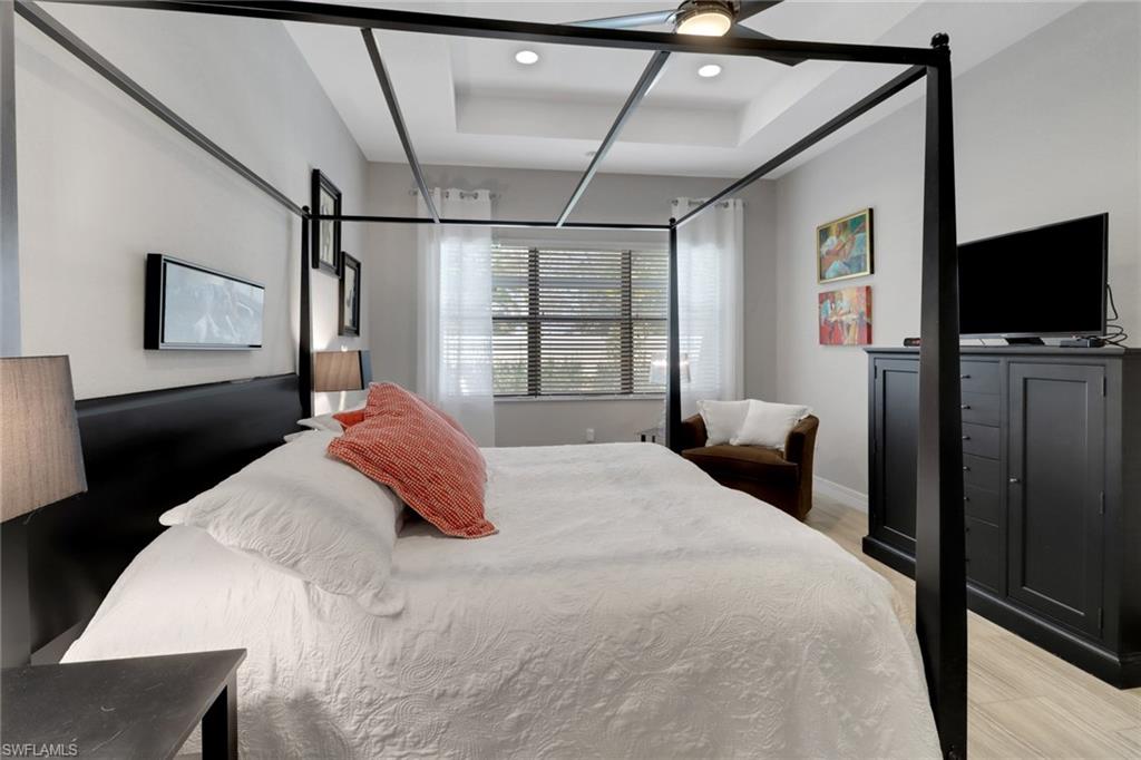 13836 Luna Drive Naples, FL 34109 - Photo 23 of 36 a bedroom with a bed a flat screen tv and a chandelier