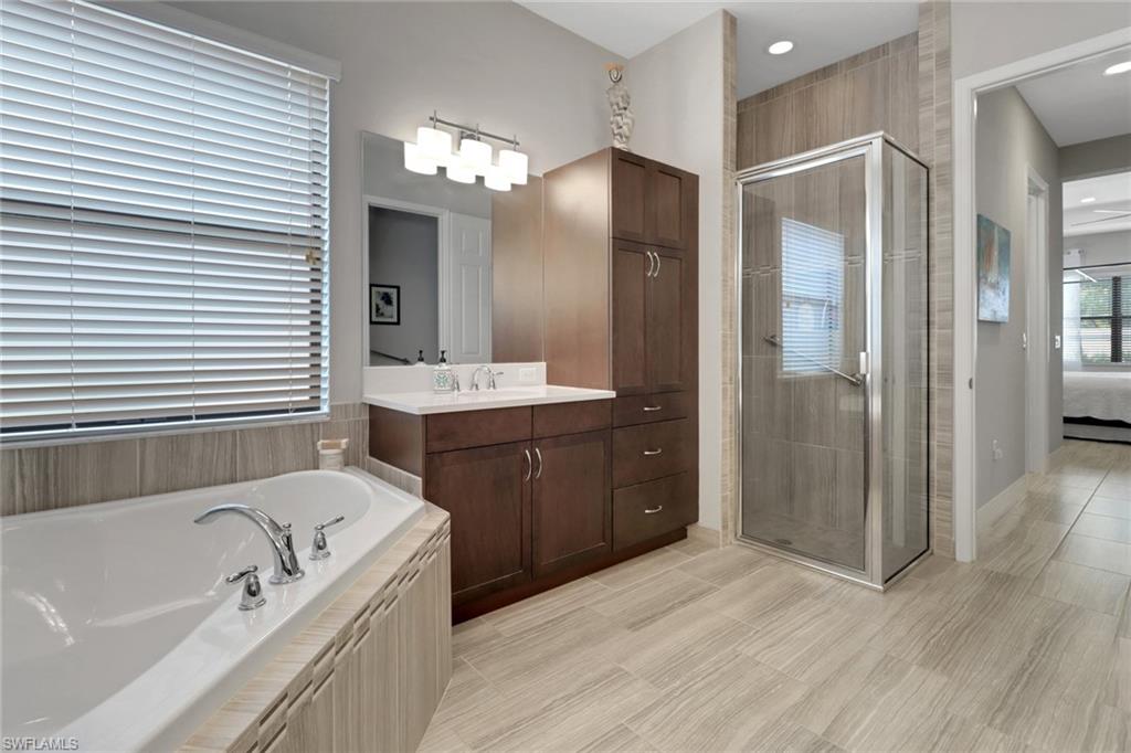 13836 Luna Drive Naples, FL 34109 - Photo 26 of 36 a bathroom with a tub a sink and mirror