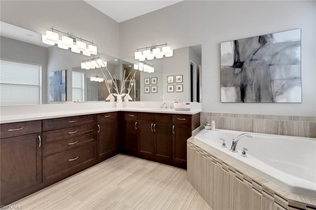 13836 Luna Drive Naples, FL 34109 - Photo 27 of 36 a bathroom with a tub a sink double vanity and a mirror
