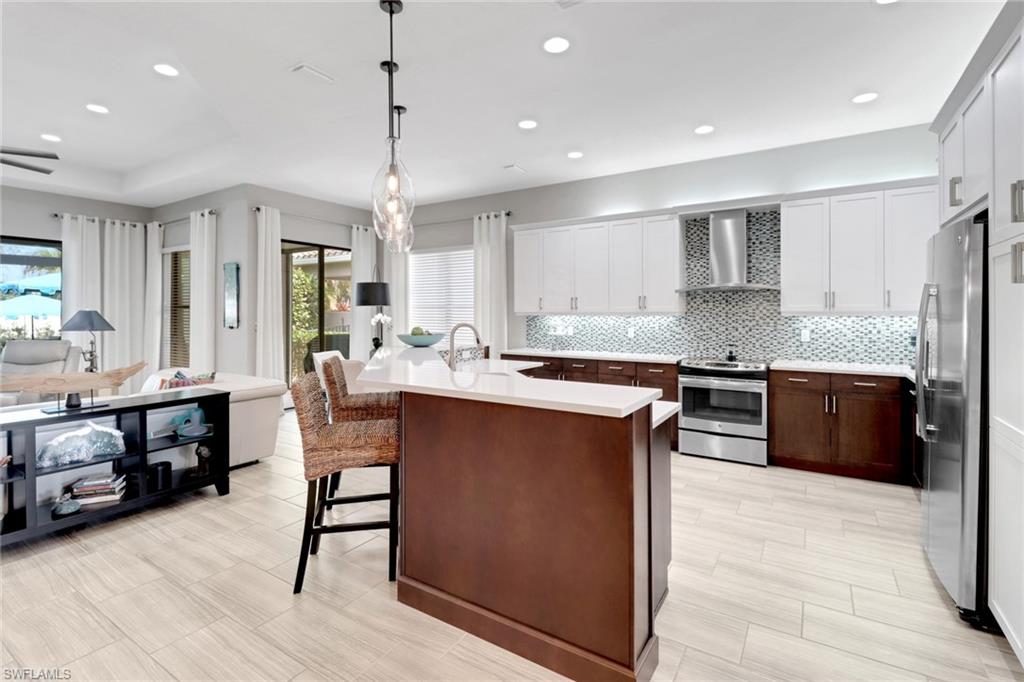 13836 Luna Drive Naples, FL 34109 - Photo 8 of 36 a kitchen with stainless steel appliances kitchen island granite countertop a stove a sink a refrigerator and a cabinets