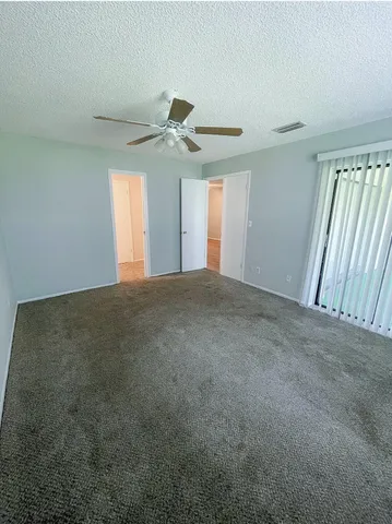 a view of a big room with windows and ceiling fan
