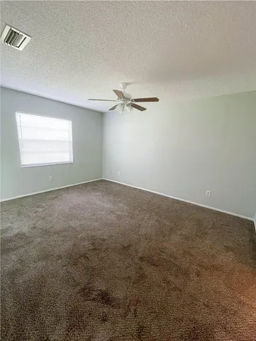 an empty room with a ceiling fan and window
