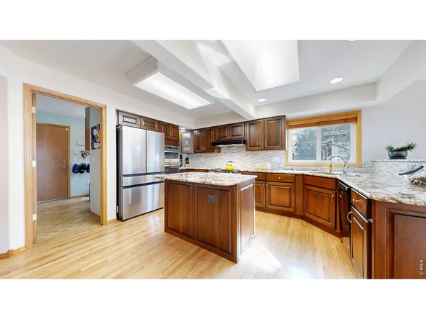 a kitchen with stainless steel appliances kitchen island granite countertop a sink refrigerator and cabinets