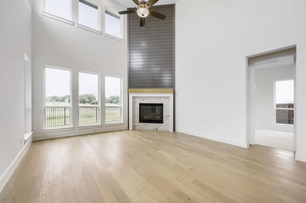 733 Red Cedar Road Haslet, TX 76052 - Photo 5 of 28 Open concept living area featuring a two-story ceiling, light wood-finish flooring, and a contemporary fireplace with a marble surround and wood mantel