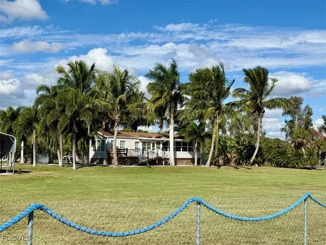 a view of a swimming pool with a lawn chairs under palm trees
