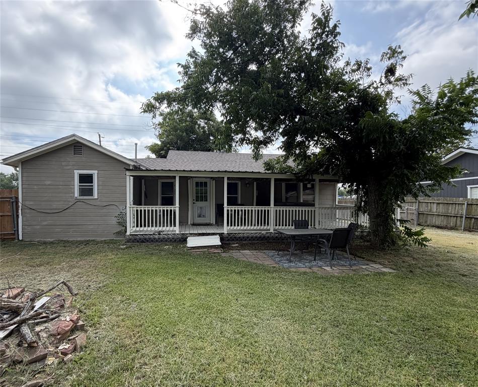 267 North Katy Road Elm Mott, TX 76640 - Photo 19 of 21 Expansive backyard featuring a covered porch with white railing, paved patio area, and a large mature tree providing natural shade