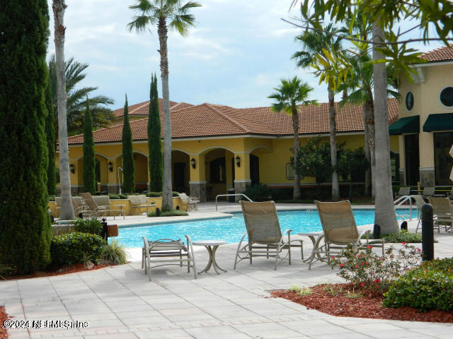 9745 Touchton Road, Unit 1805 Jacksonville, FL 32246 - Photo 11 of 77 a view of a patio with couches table and chairs potted plants and palm tree