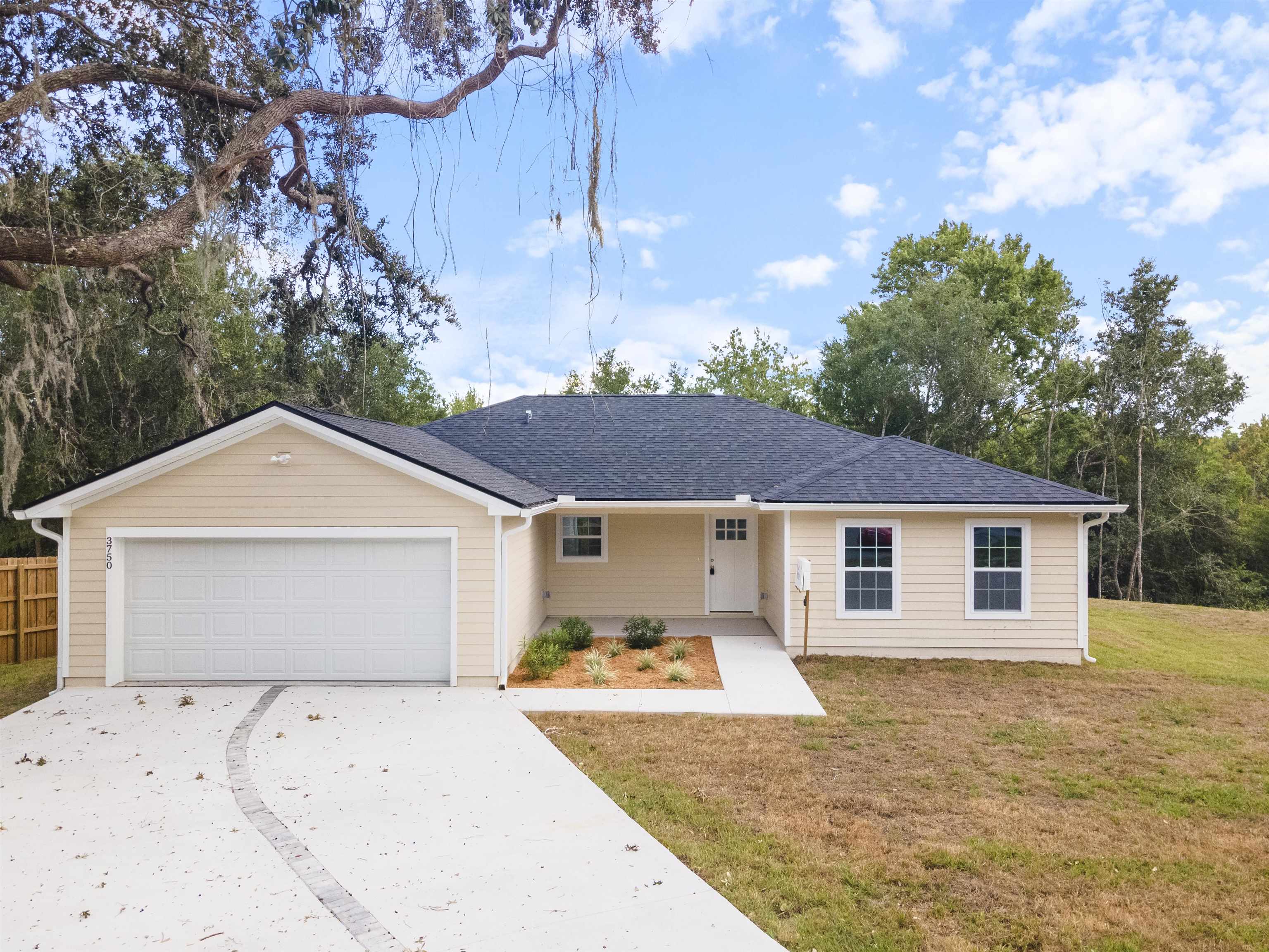 a view of a white house with a yard and large tree