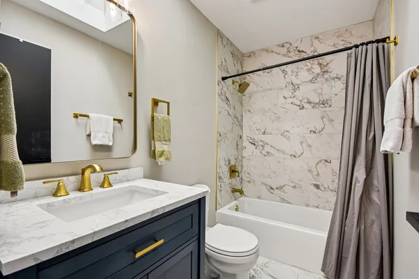 a bathroom with a granite countertop sink a mirror a shower and a bathtub