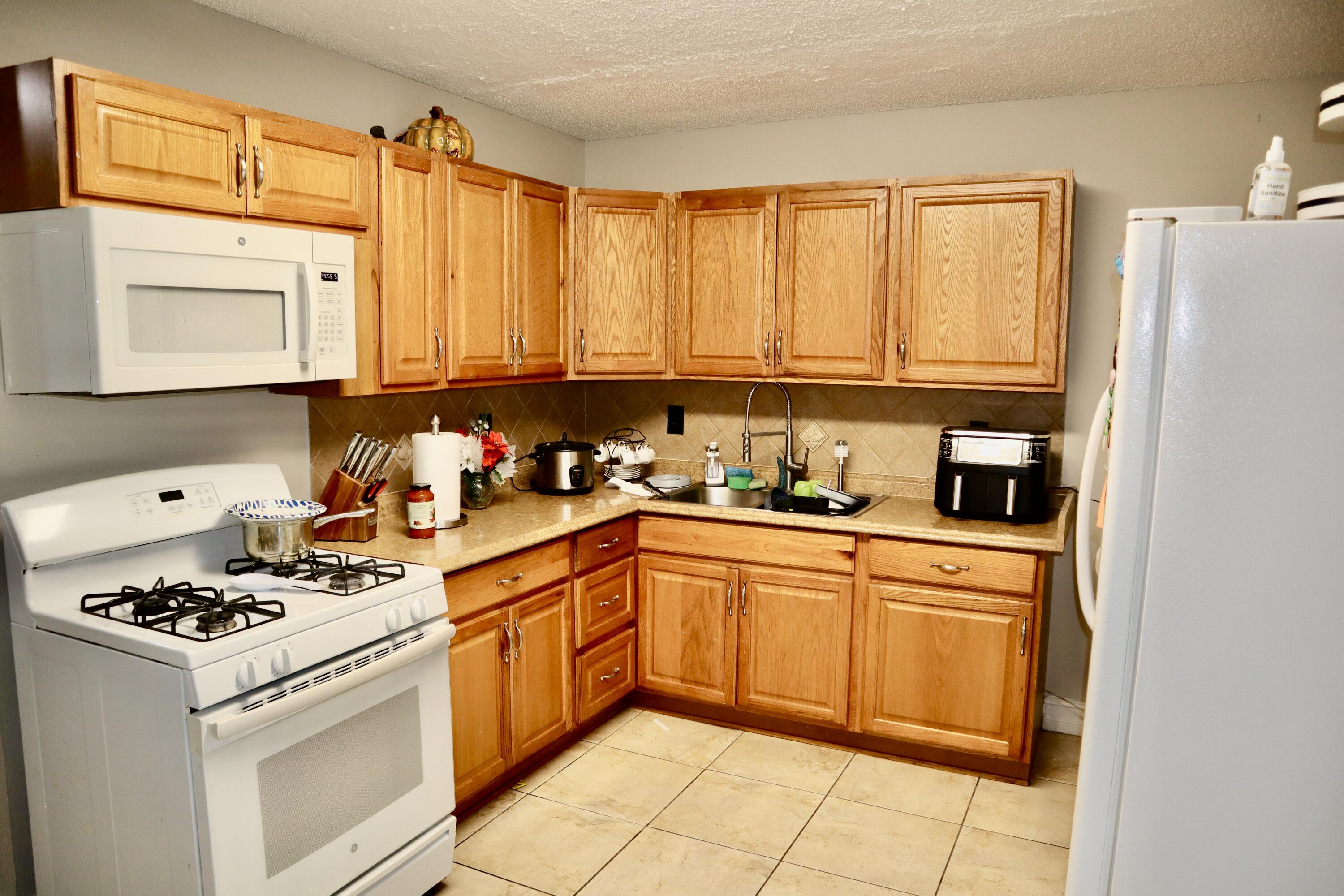 5905 Triphammer Road Lake Worth, FL 33463 - Photo 4 of 8 a kitchen with stainless steel appliances a stove a sink and a refrigerator
