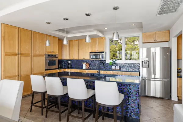 a dining hall with stainless steel appliances kitchen island granite countertop a table and chairs
