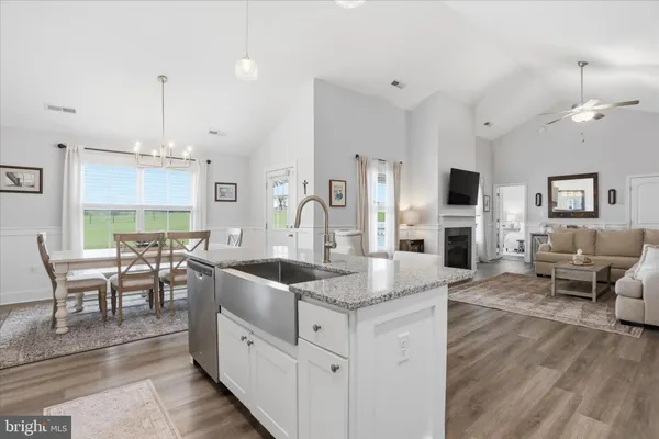 a open kitchen with stainless steel appliances granite countertop a stove top oven a sink dishwasher a dining table and chairs with wooden floor