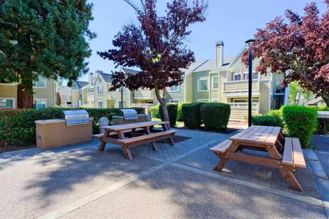 a view of a patio with dining table and chairs under an umbrella with a fire pit