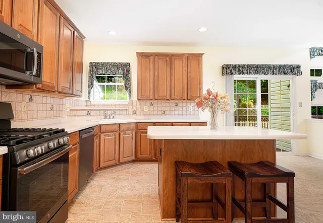a kitchen with kitchen island granite countertop a stove top oven a sink dishwasher and a refrigerator