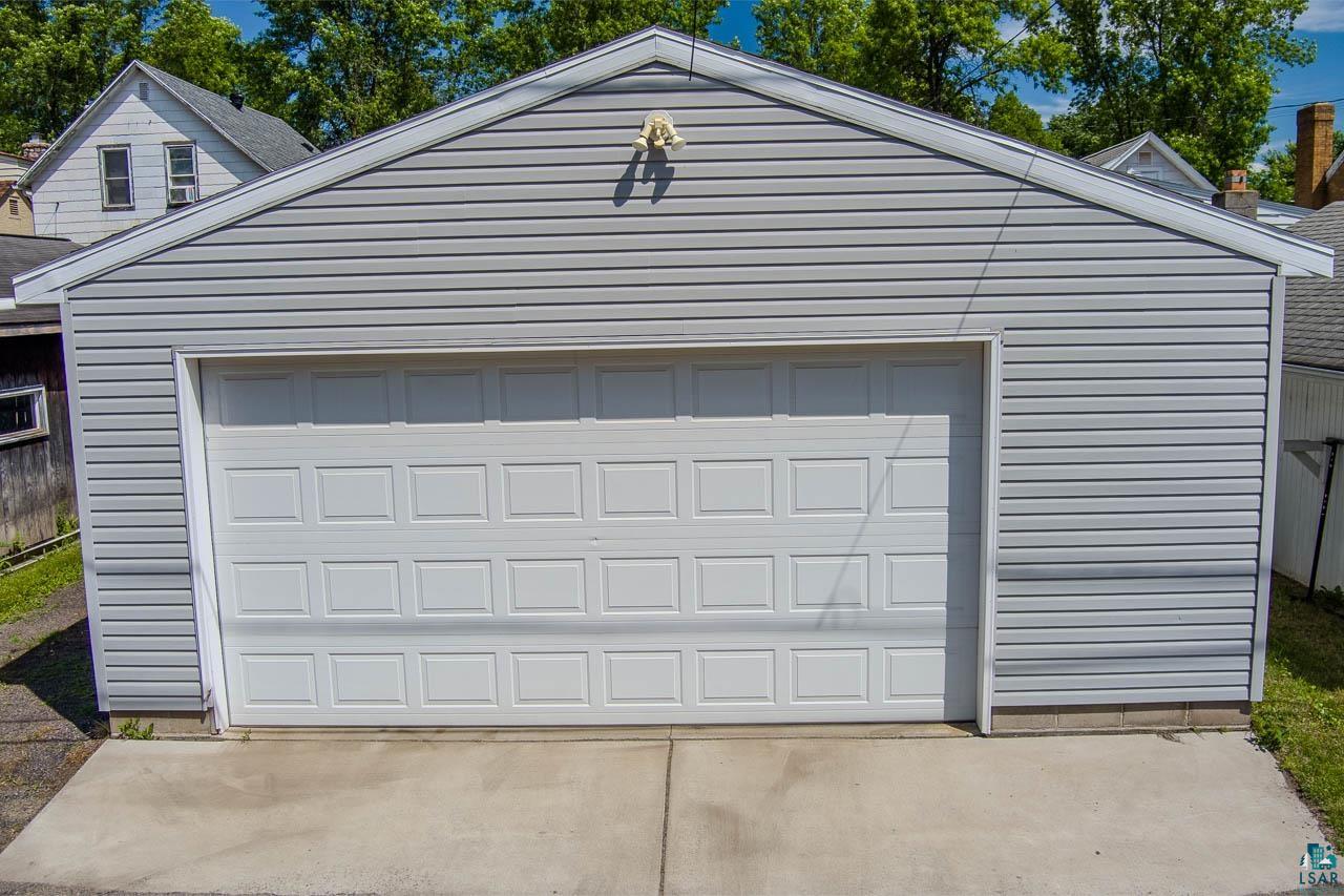 508 10th Street South Virginia, MN 55792 - Photo 32 of 43 Detached garage featuring light gray horizontal siding, a white paneled garage door, and a concrete approach