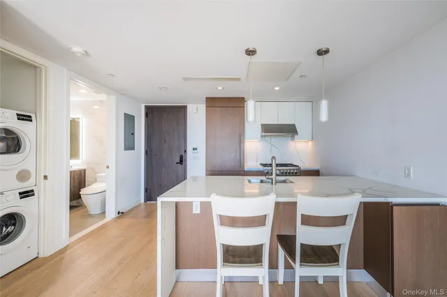 a kitchen with stainless steel appliances kitchen island granite countertop a dining table chairs and white cabinets