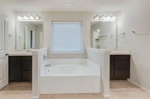 a bathroom with a bathtub and a double vanity sink