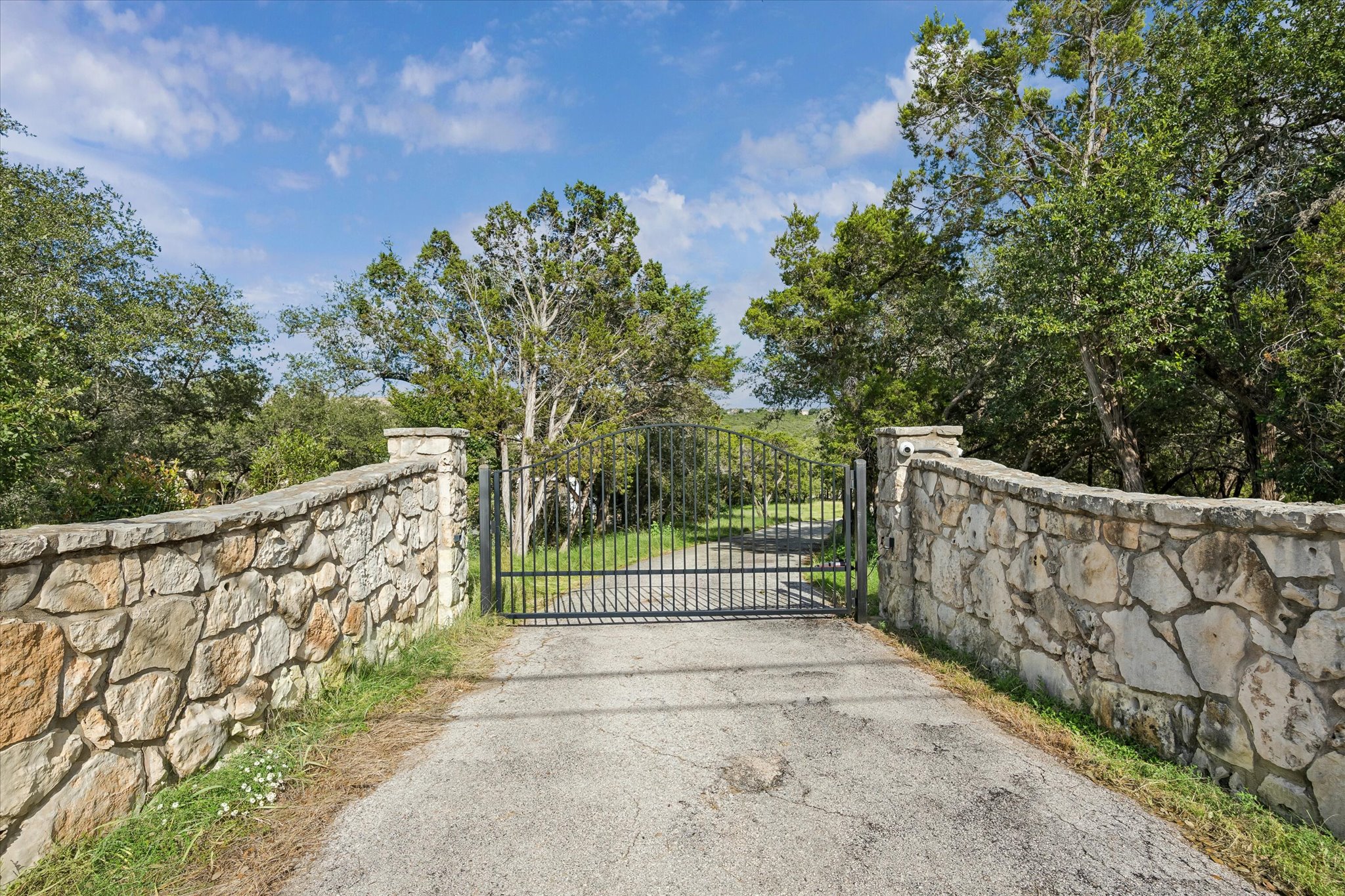 3719 Bee Creek Road Spicewood, TX 78669 - Photo 3 of 40 A private stone wall entry gate welcomes you to an estate surrounded by verdant trees.