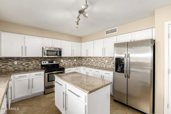 a kitchen with stainless steel appliances granite countertop a sink a stove a refrigerator a center island and cabinets