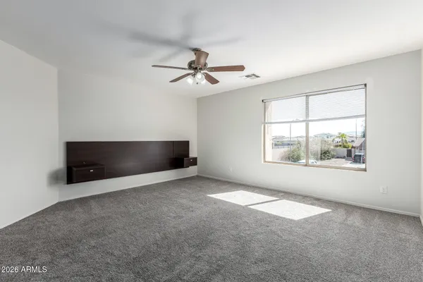 an empty room with windows and ceiling fan