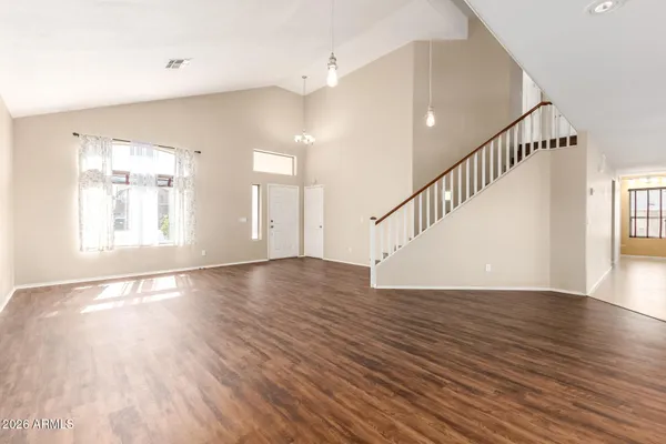 a view of an empty room with wooden floor and staircase