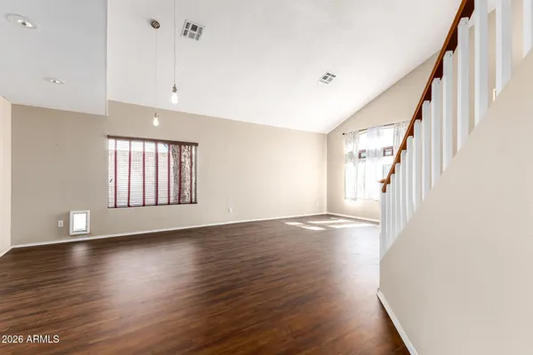 a view of an empty room with wooden floor and stairs