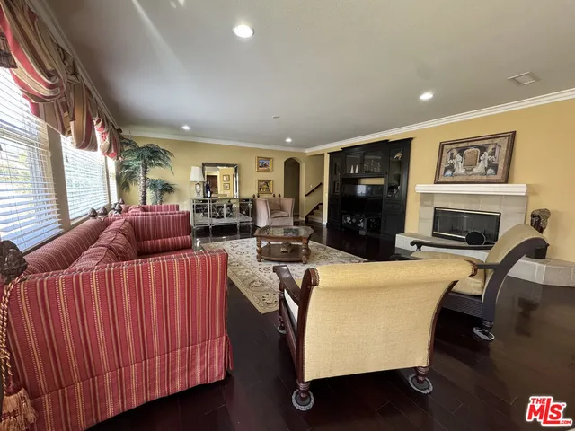 a living room with furniture a flat screen tv and a refrigerator