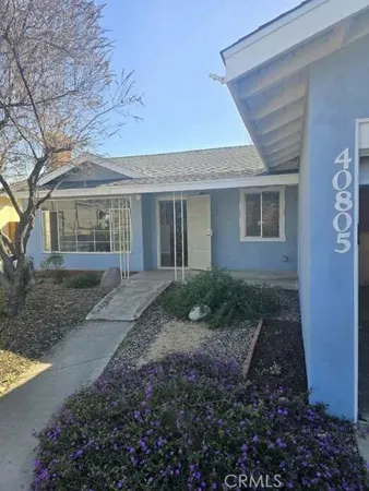 a view of a brick house with yard and plants