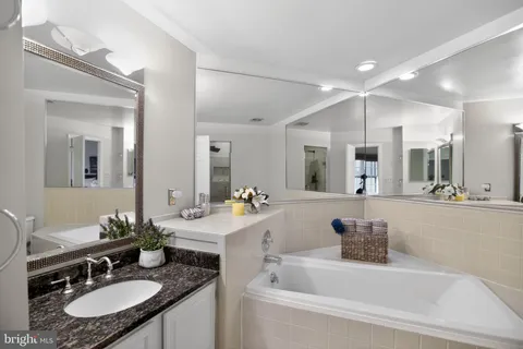 a bathroom with a granite countertop sink a mirror a bathtub and vanity
