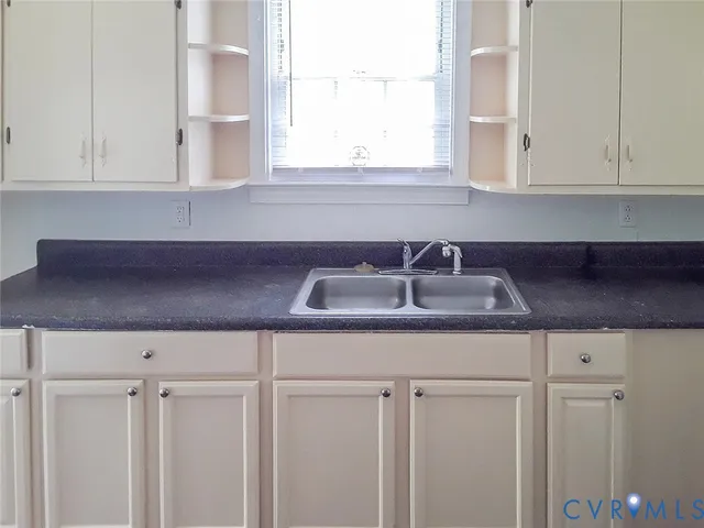 a kitchen with white cabinets and a window