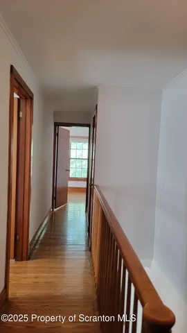 a view of a hallway with wooden floor and stairs