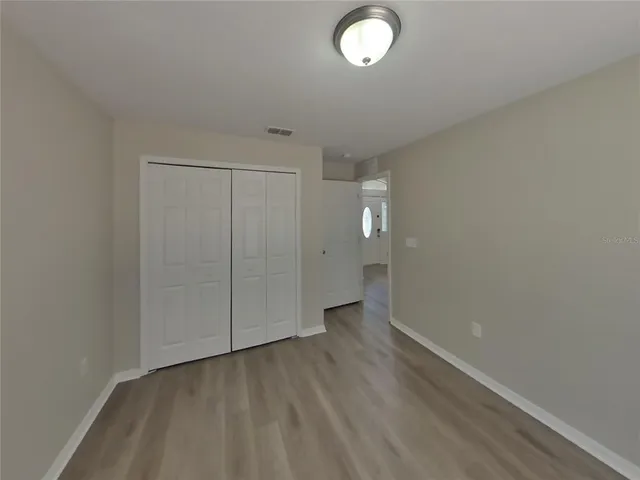 an empty room with wooden floor and mirror