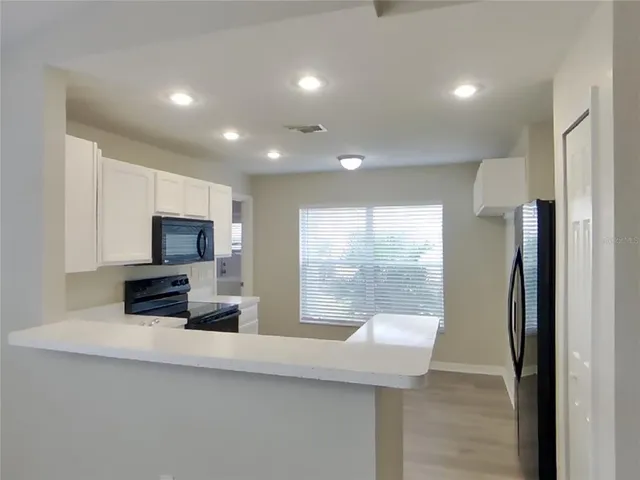 a kitchen with stainless steel appliances a stove a sink a microwave a refrigerator and cabinets