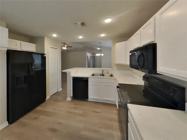 a large white kitchen with a sink and stainless steel appliances