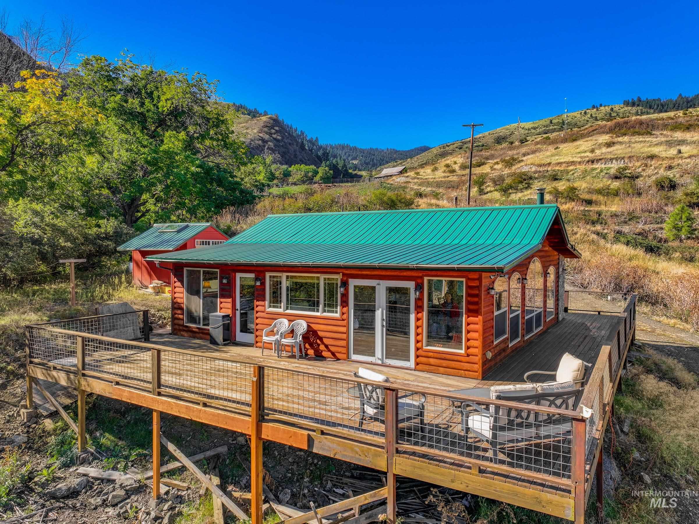 Rear view of property featuring a deck with mountain view, log veneer siding, a metal roof, and french doors