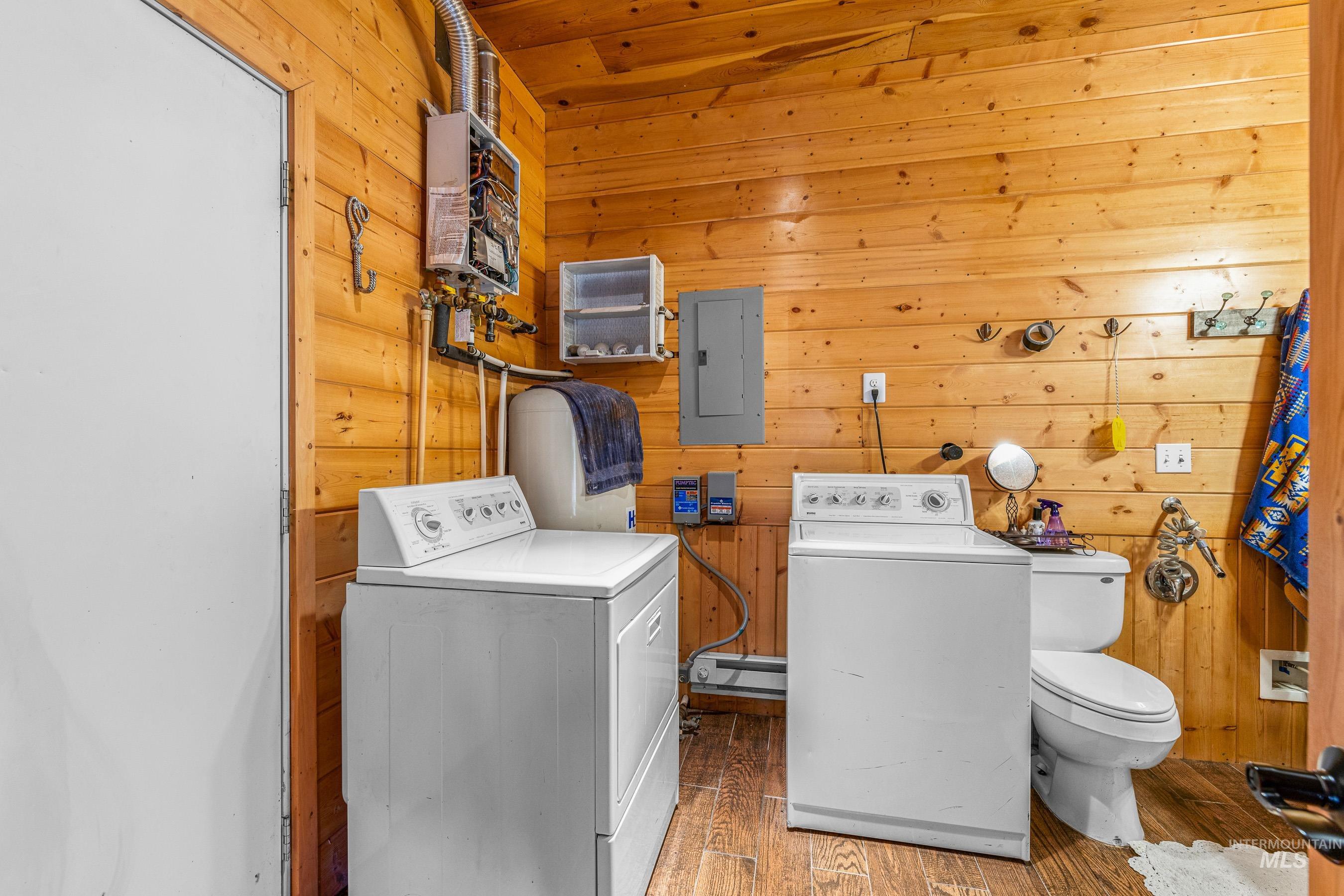 236 Seven U Ranch Road Lucile, ID 83542 - Photo 15 of 26 Laundry room with wooden walls, washer and dryer, wood finished floors, electric panel, and a baseboard heating unit