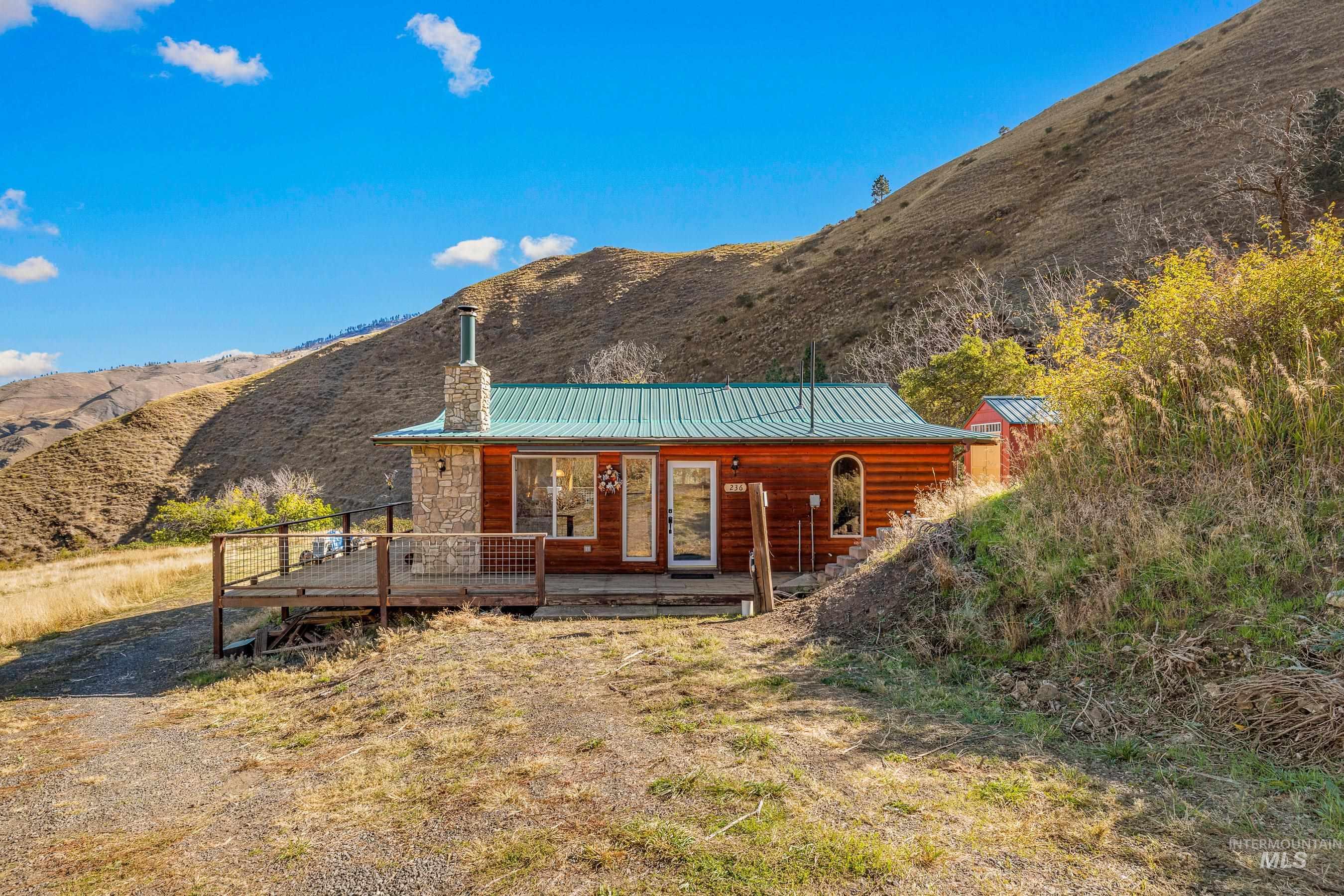 236 Seven U Ranch Road Lucile, ID 83542 - Photo 17 of 26 Back of property with a chimney, a metal roof, and a deck with mountain view