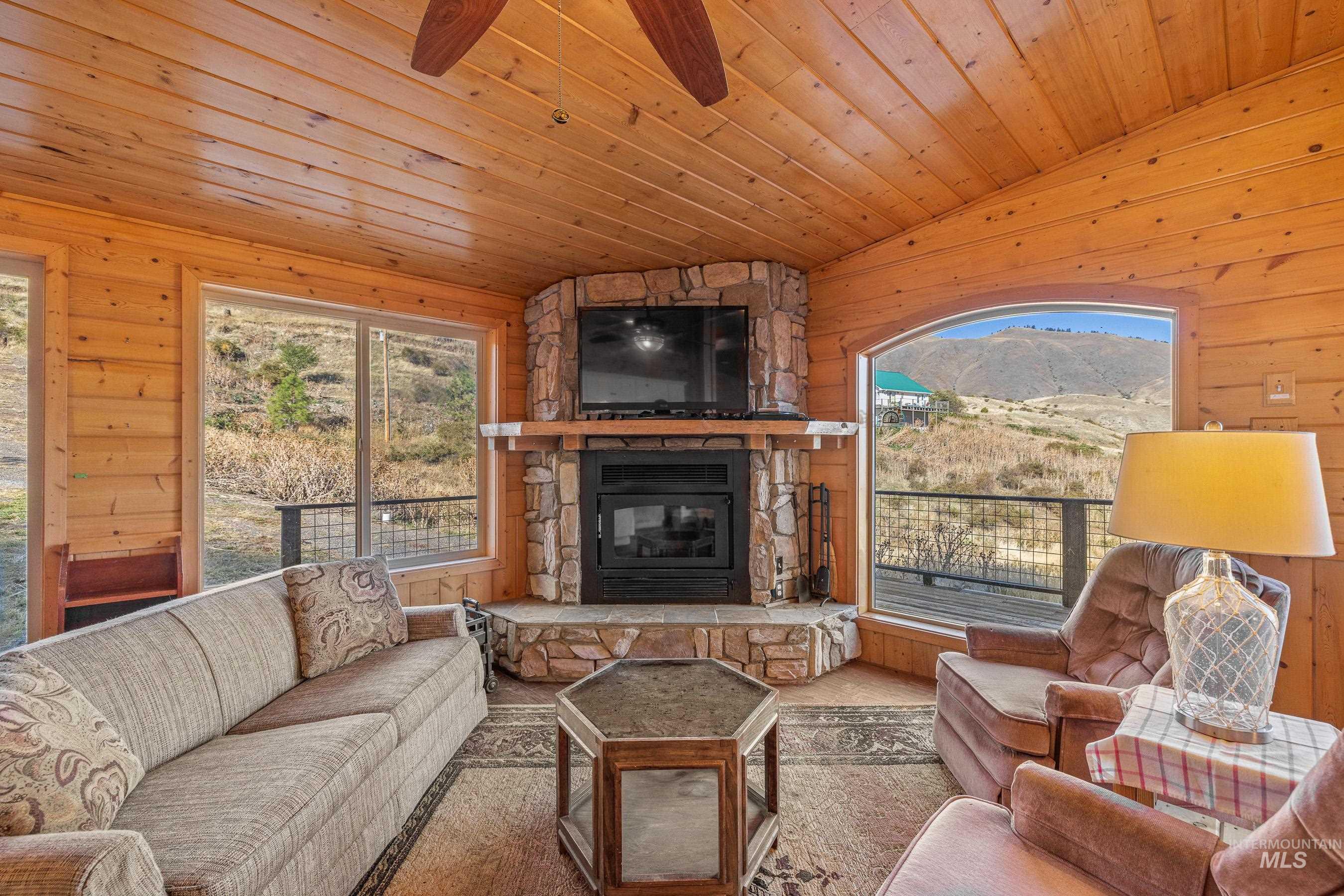 236 Seven U Ranch Road Lucile, ID 83542 - Photo 2 of 26 Living room featuring wood walls, lofted ceiling, plenty of natural light, a fireplace, and wood ceiling