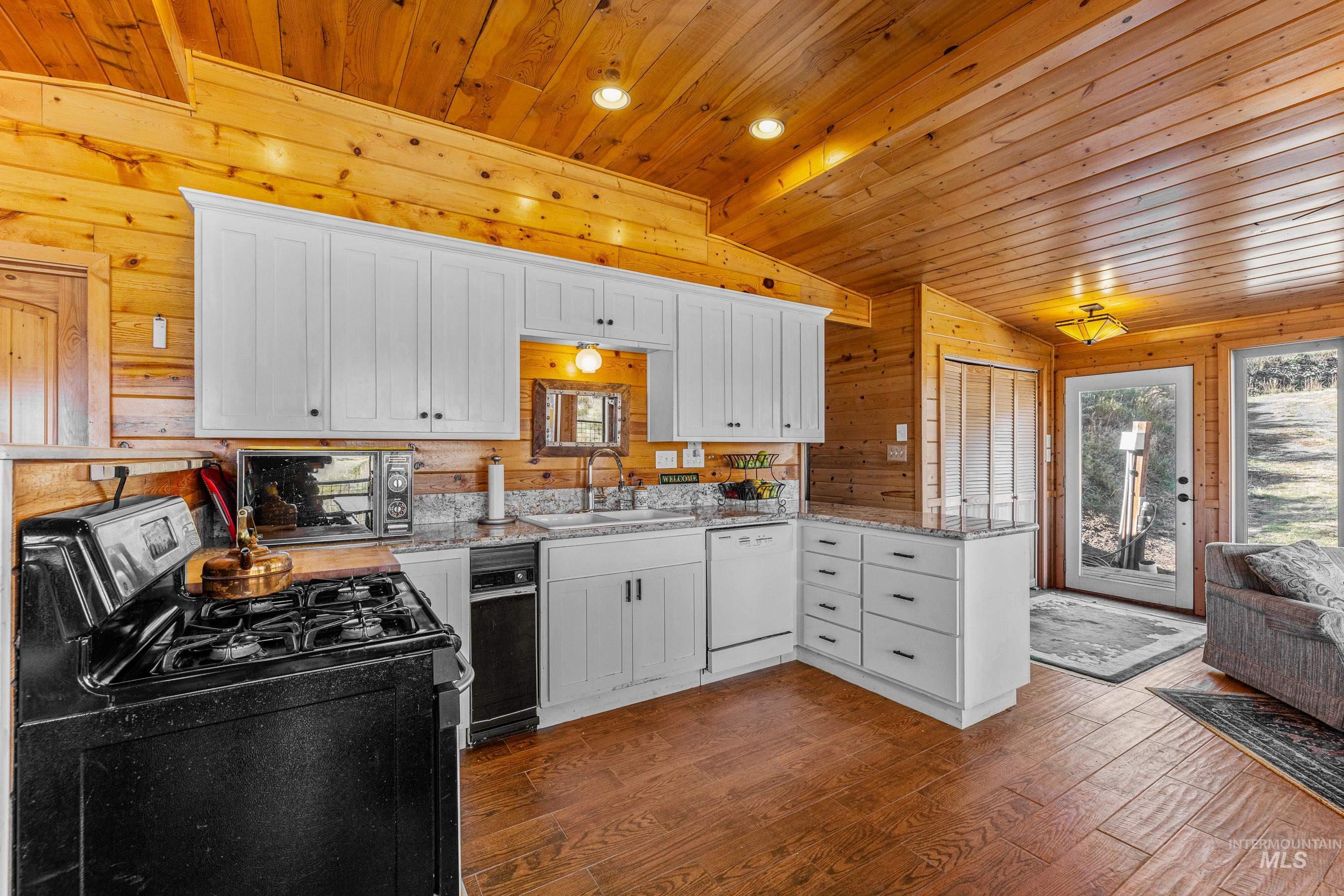 236 Seven U Ranch Road Lucile, ID 83542 - Photo 7 of 26 Kitchen featuring gas stove, white cabinets, dark wood-style floors, lofted ceiling, and wood walls