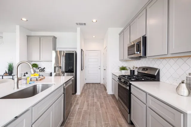a kitchen with stainless steel appliances granite countertop a sink stove refrigerator and cabinets