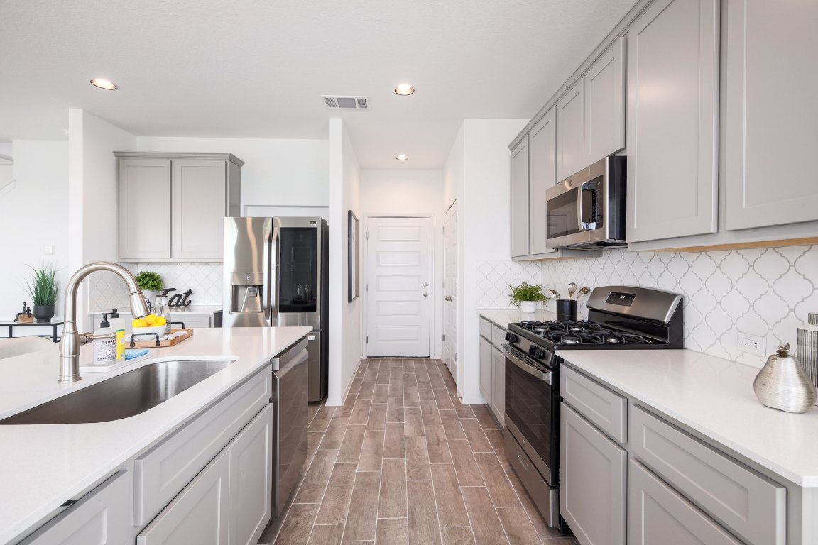 1408 Flint Knapper Drive Georgetown, TX 78626 - Photo 11 of 32 a kitchen with stainless steel appliances granite countertop a sink stove refrigerator and cabinets