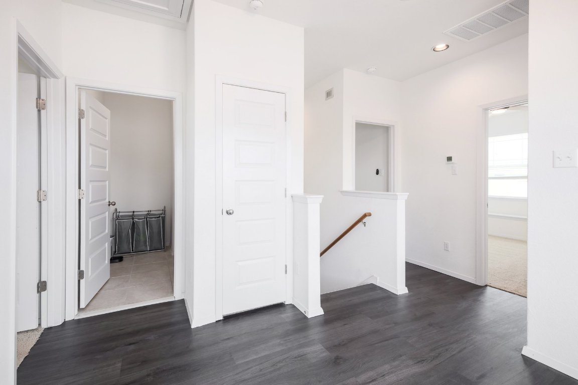 1408 Flint Knapper Drive Georgetown, TX 78626 - Photo 18 of 32 an empty room with wooden floor and a hallway