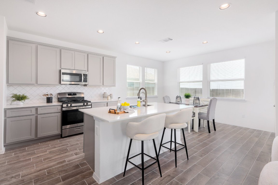 1408 Flint Knapper Drive Georgetown, TX 78626 - Photo 10 of 32 a kitchen with stainless steel appliances a stove a sink a refrigerator white cabinets and wooden floor
