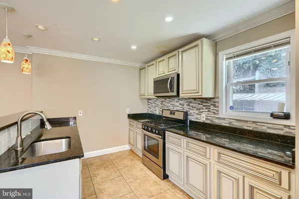a kitchen with granite countertop a stove sink and microwave