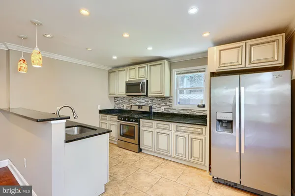 a kitchen with stainless steel appliances granite countertop a refrigerator a sink a stove and oven